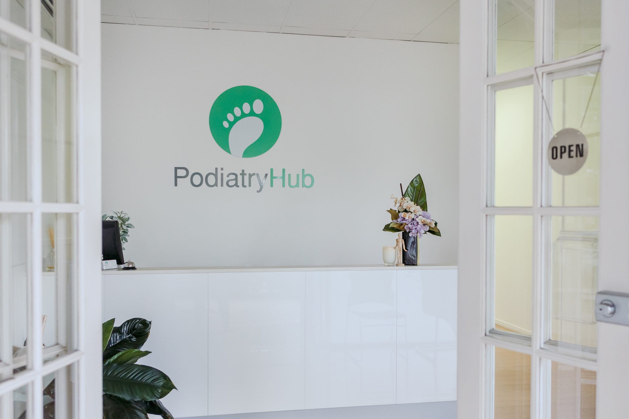 Podiatry hub clinic reception desk with their logo on the back wall